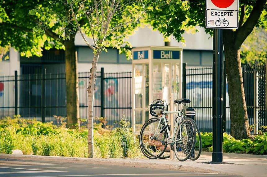 Bicycle parked on Montreal city street with greenery.
