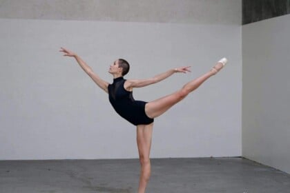Ballerina performing an arabesque in dance studio.