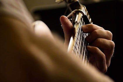 Close-up of musician playing acoustic guitar.
