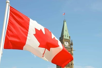 Canadian flag waving in front of Parliament Hill.