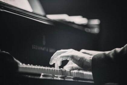Piano keys being played at a candlelit tribute concert.