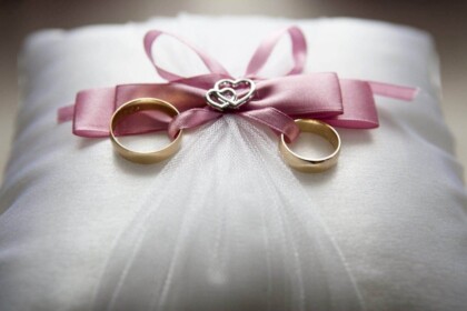 Elegant engagement rings on cushion with pink ribbon.