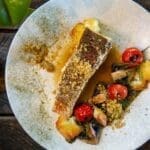 Elegant plated sablefish with vegetables and garnish.