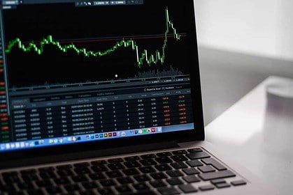 Laptop displaying stock market investment charts.