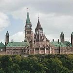 Historic stone building with towers against cloudy sky.