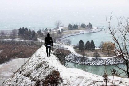 Person overlooking snowy Scarborough Bluffs in winter.
