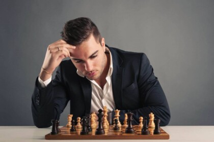 Focused man contemplating chess strategy on dark background.