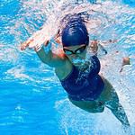 Female athlete performing freestyle stroke in swimming pool.