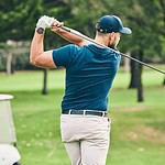 Man practicing golf swing on the course in summer.