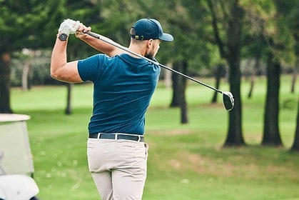 Man practicing golf swing on the course in summer.