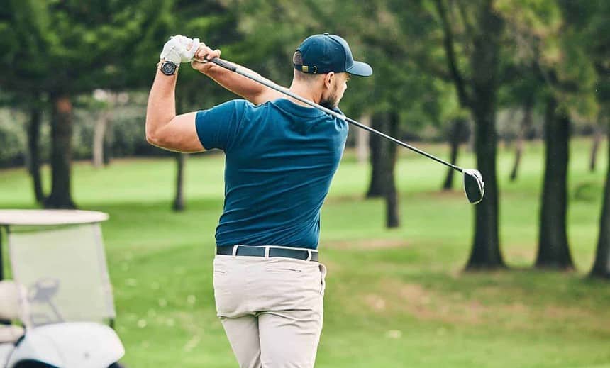 Man practicing golf swing on the course in summer.