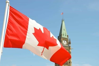 Canadian flag waving in front of Parliament Hill.
