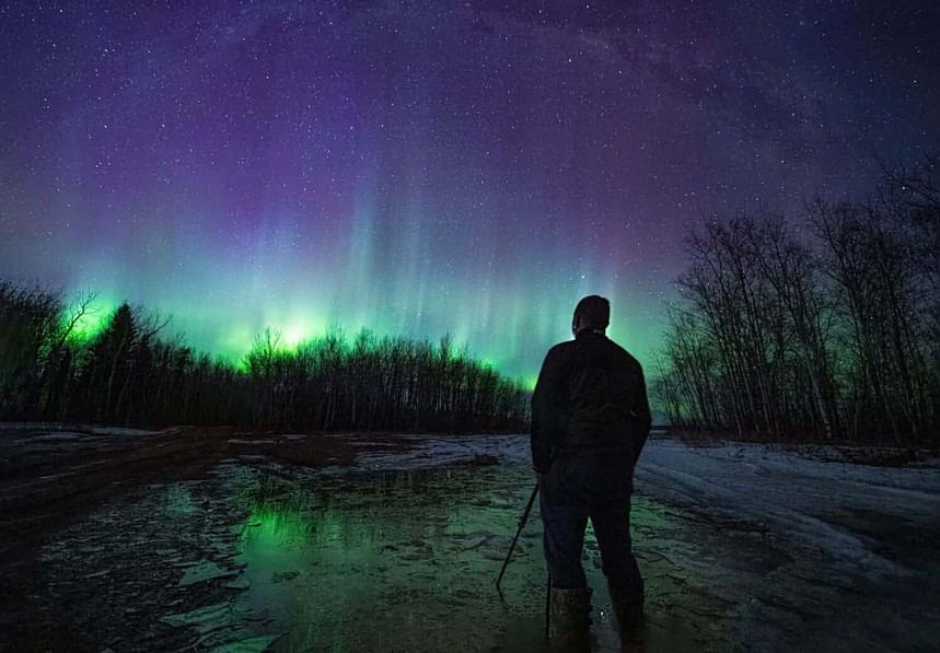 Man witnessing Aurora Borealis in Canadian wilderness.
