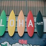 Colorful surfboards with Aloha sign on wall.