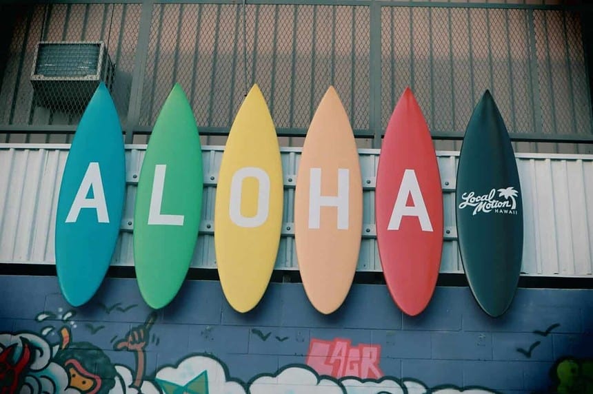 Colorful surfboards with Aloha sign on wall.