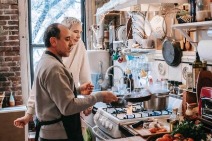Two chefs preparing food with stainless steel cookware.