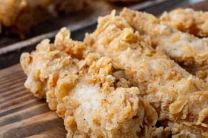 Golden crispy fried chicken on wooden board.