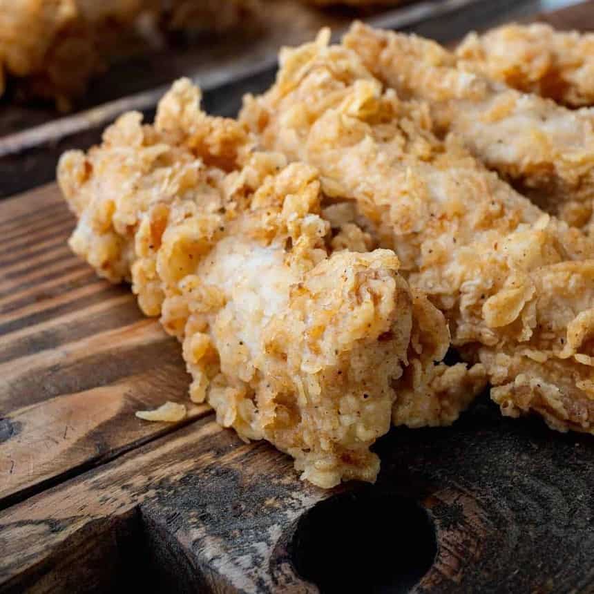 Golden crispy fried chicken on wooden board.