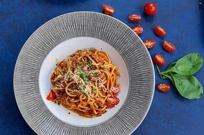 Bowl of fresh spaghetti with tomato sauce and basil garnish