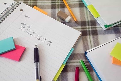 Korean language study materials with notebook and colorful pens.
