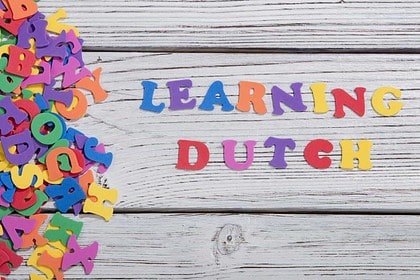 Colorful magnetic letters spelling Learning Dutch on a wooden surface.