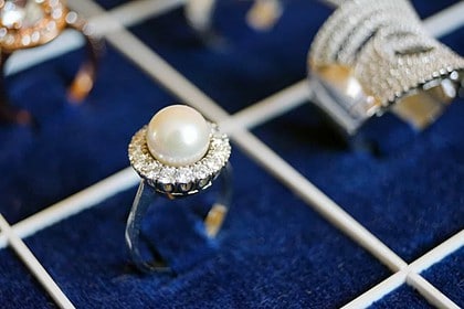 Elegant pearl ring displayed on a blue velvet surface.