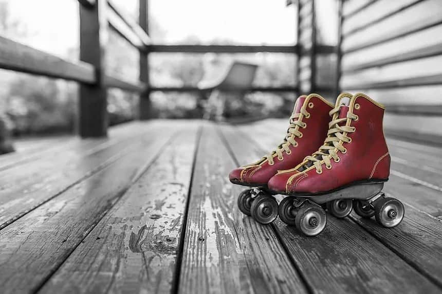 Red vintage roller skates on wooden floor.