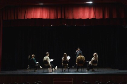 Actors rehearsing on dimly lit theater stage