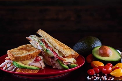 Turkey bacon club sandwich with avocado and tomatoes.