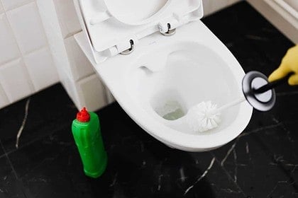 Plunger and bottle next to an open toilet.