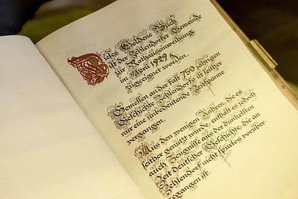 Open vintage book with illuminated manuscript page.