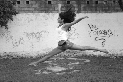 Woman jumping in front of graffiti wall in black and white.