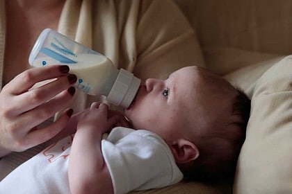 Infant being fed with a bottle by caregiver.