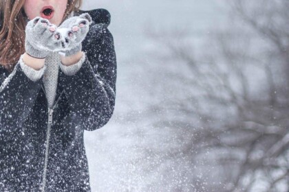 Woman in winter coat over formal attire in snow.