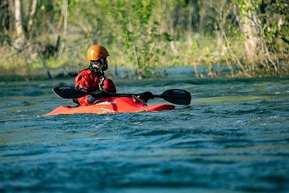 Person kayaking in river wearing safety gear