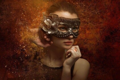 Elegant woman wearing a decorative mask with a thoughtful expression.