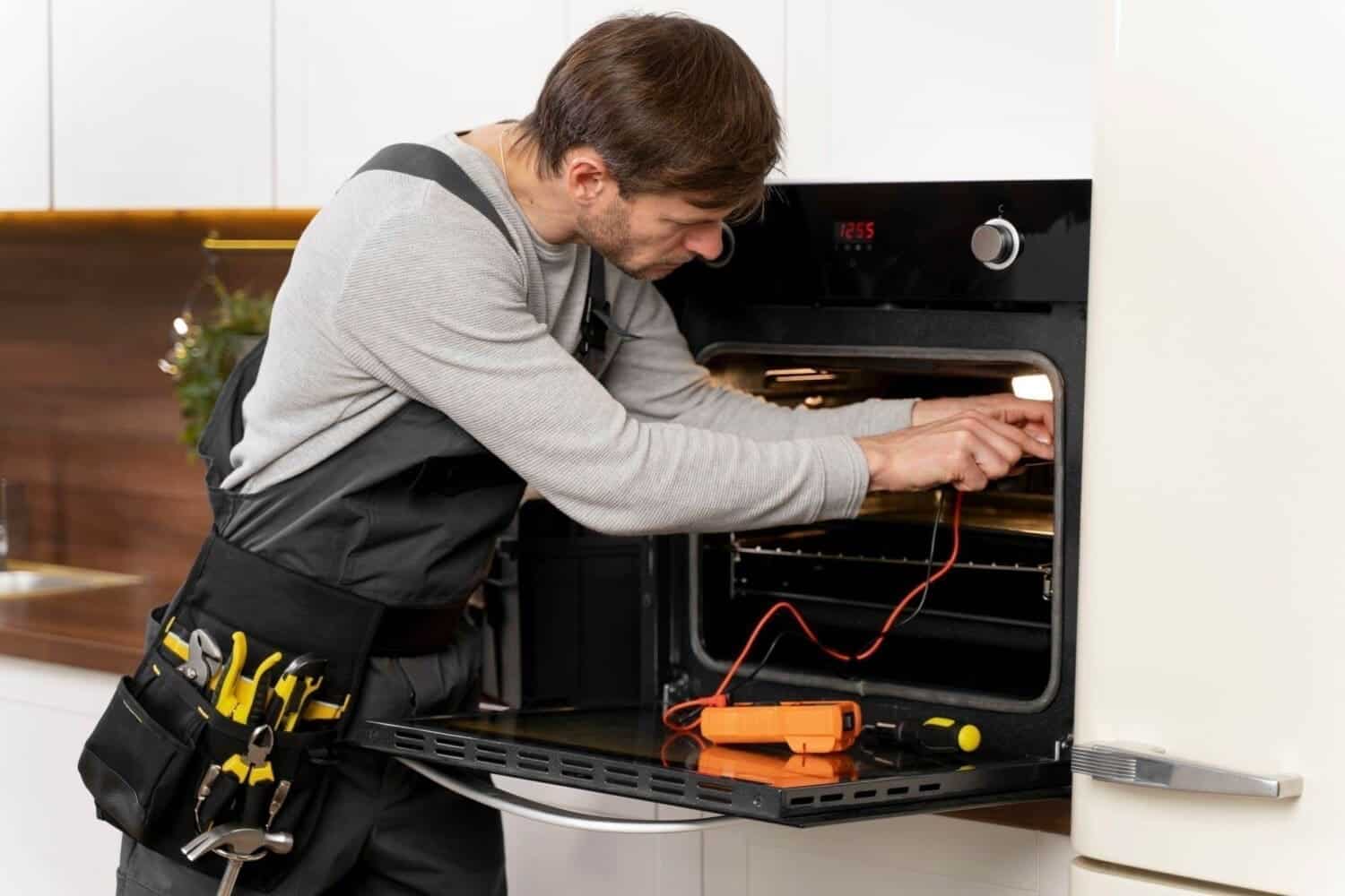 Technician repairing an oven in a kitchen.