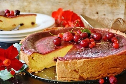 Freshly baked cheesecake adorned with berries on a table.