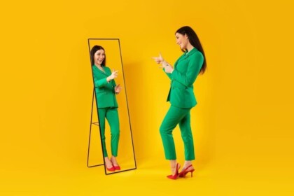 Fashionable woman in green suit admiring herself in mirror.
