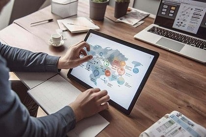 Person analyzing digital marketing data on tablet at desk.