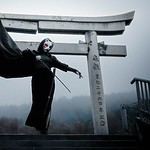 Samurai sword practice at a torii gate in misty surroundings.