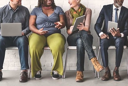 Diverse team engaged with laptops and mobile devices.