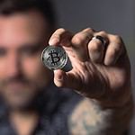 Man displaying a silver Bitcoin coin.