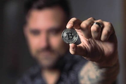 Man displaying a silver Bitcoin coin.