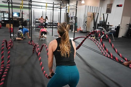 Woman working out with battle ropes in a gym.