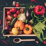 Organic vegetables in crate on dark background.