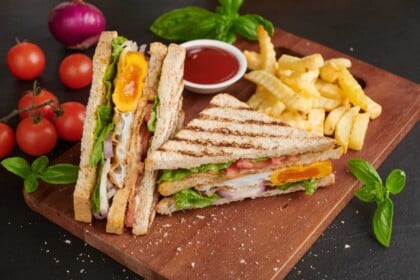 Appetizing bacon egg club sandwich with golden fries.