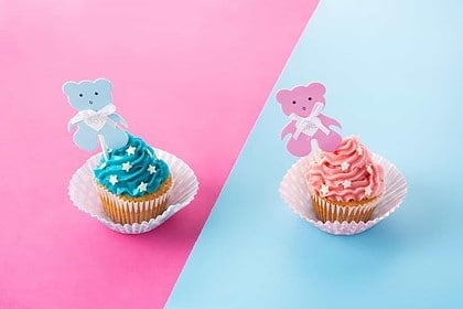 Pink and blue cupcakes for baby shower on a split background.