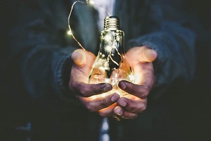 Individual presenting a light bulb, representing green energy career potential.