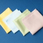 Pastel-colored microfiber cloths arranged on textured blue background.